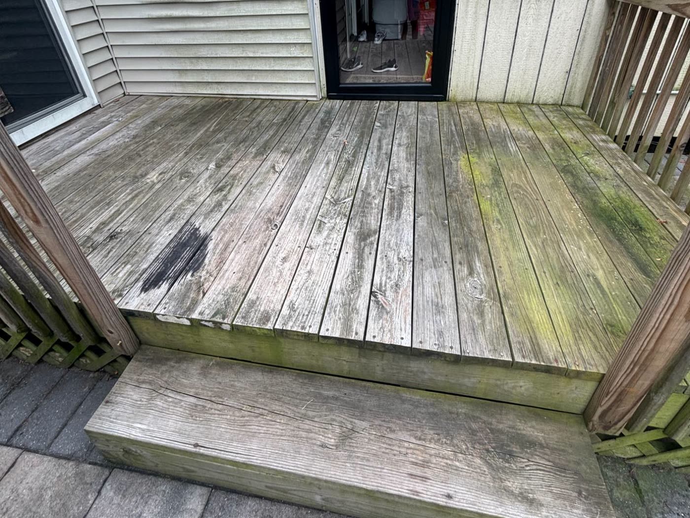 A wooden deck gone grey and green with weathering and algae