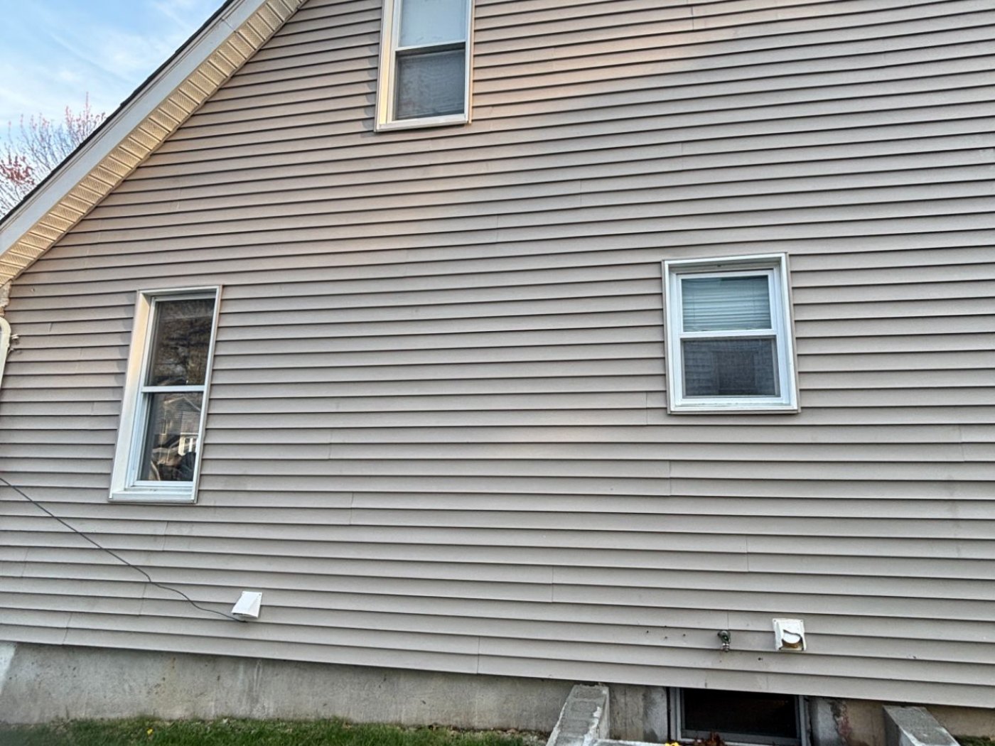 The same wall after washing — the tan siding is even and the green growth is gone